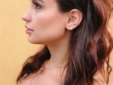 a woman with long hair wearing a necklace and earrings
