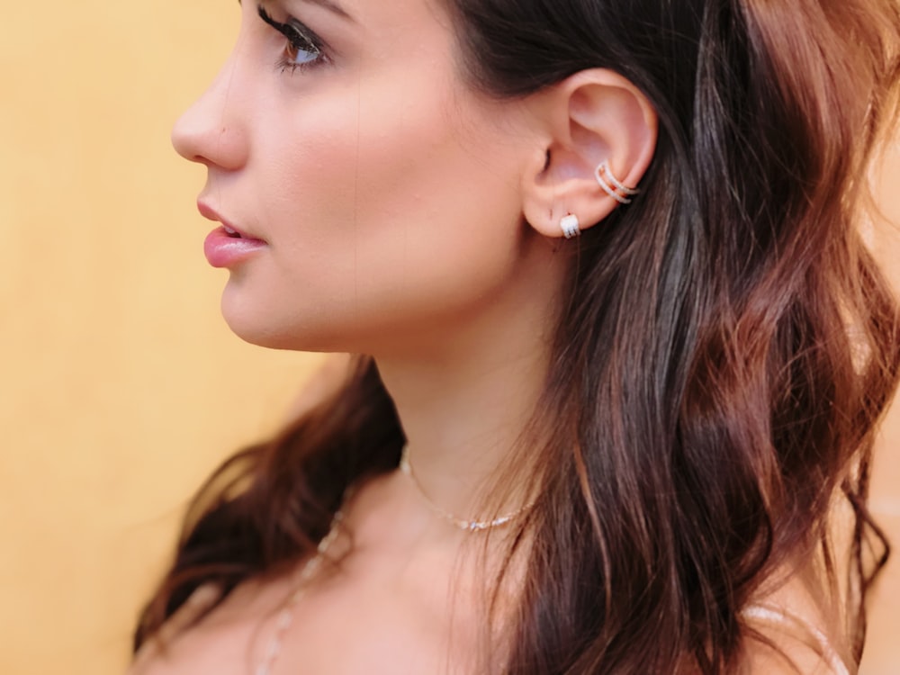 a woman with long hair wearing a necklace and earrings