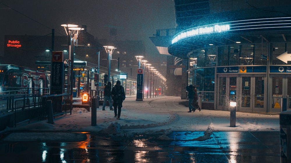 a couple of people walking down a snow covered street