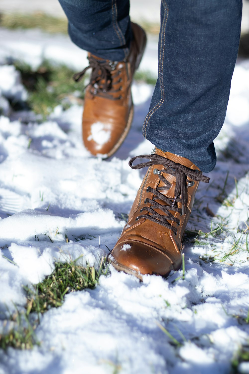 a person standing in the snow wearing brown shoes