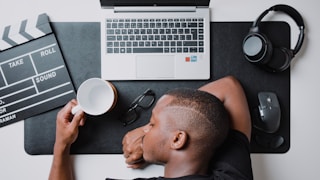 a man sitting at a desk with a laptop and headphones by Nubelson Fernandes (@nublson)