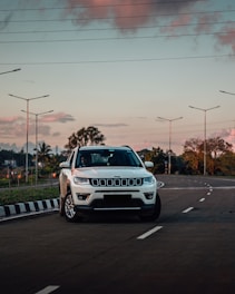 a white jeep parked on the side of a road