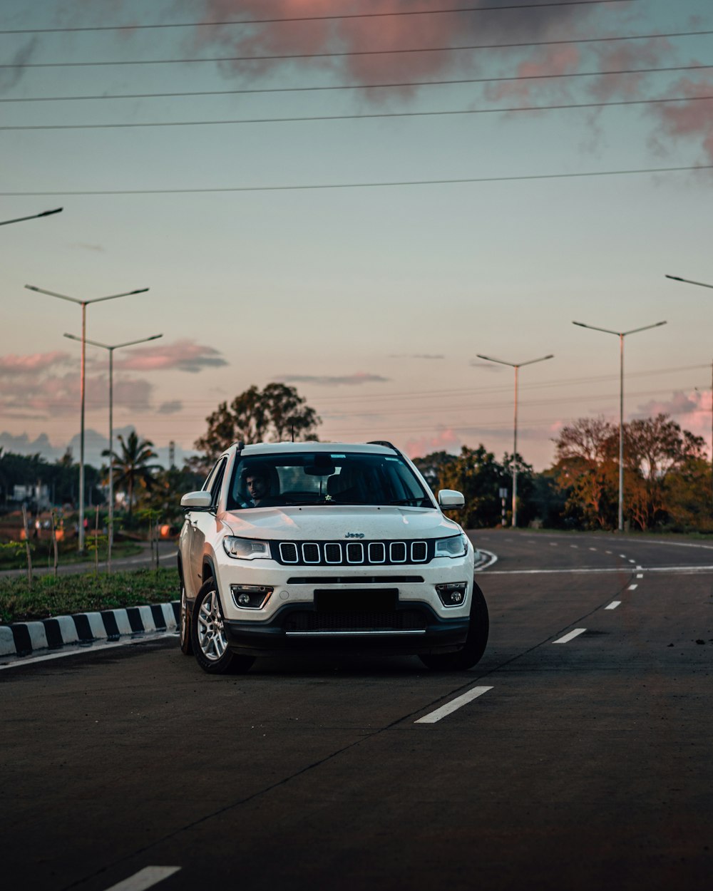 a white jeep parked on the side of a road