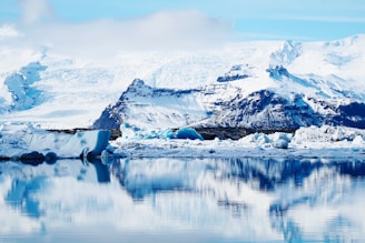 a large iceberg floating on top of a lake surrounded by mountains