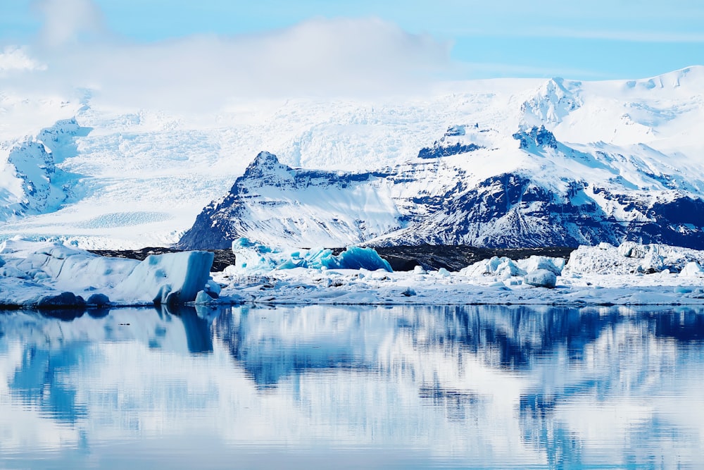 a large iceberg floating on top of a lake surrounded by mountains