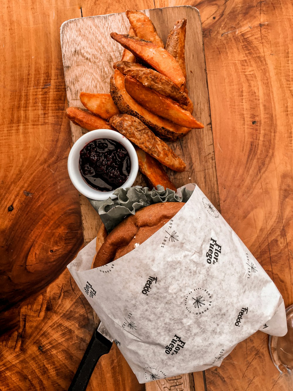 a wooden table topped with a bag of french fries