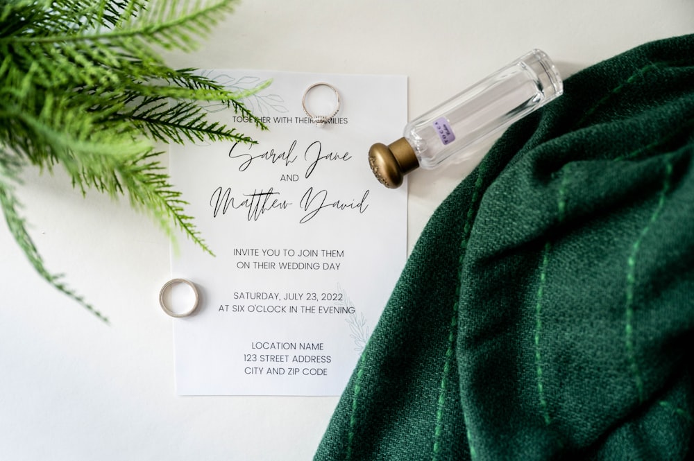 una tarjeta de boda y un anillo sobre una bufanda verde