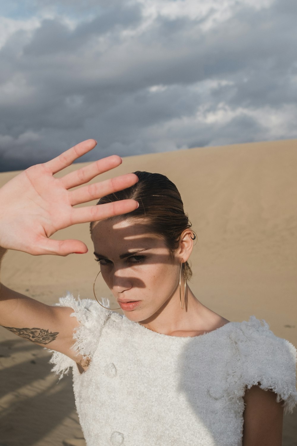 a woman in a white dress holding her hand up to her head