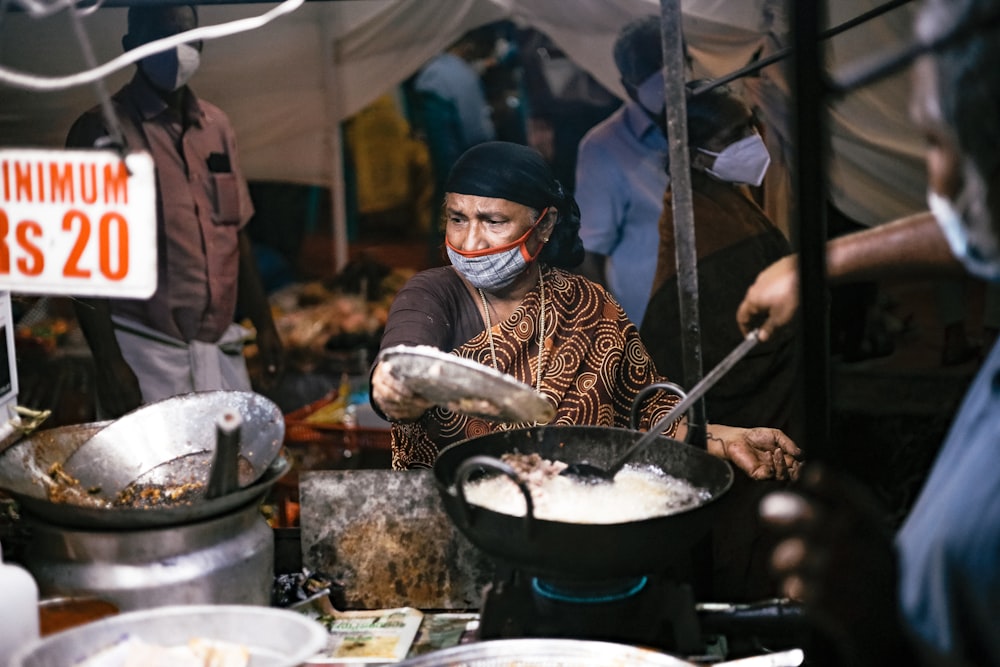 a woman wearing a face mask cooking food in a pan