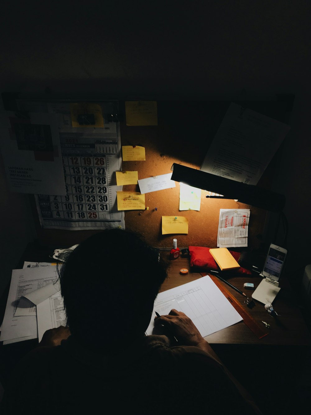 a person sitting at a desk in front of a lamp