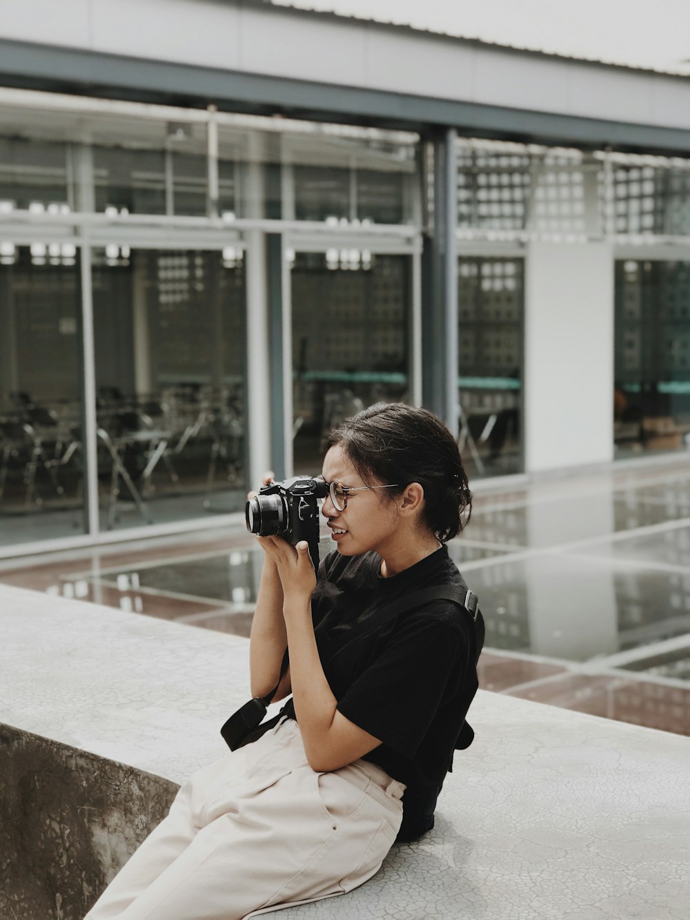 a woman sitting on a ledge with a camera