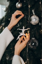 A close-up of a professional installer carefully arranging holiday lights on a tree.