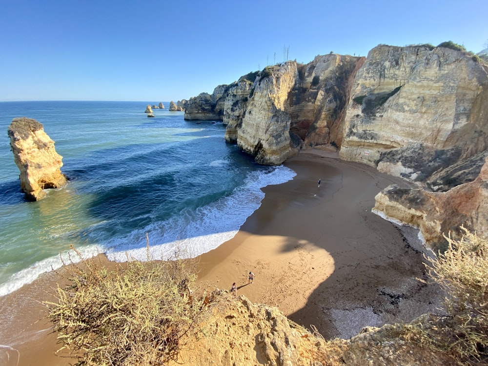 a sandy beach next to the ocean with cliffs in the background