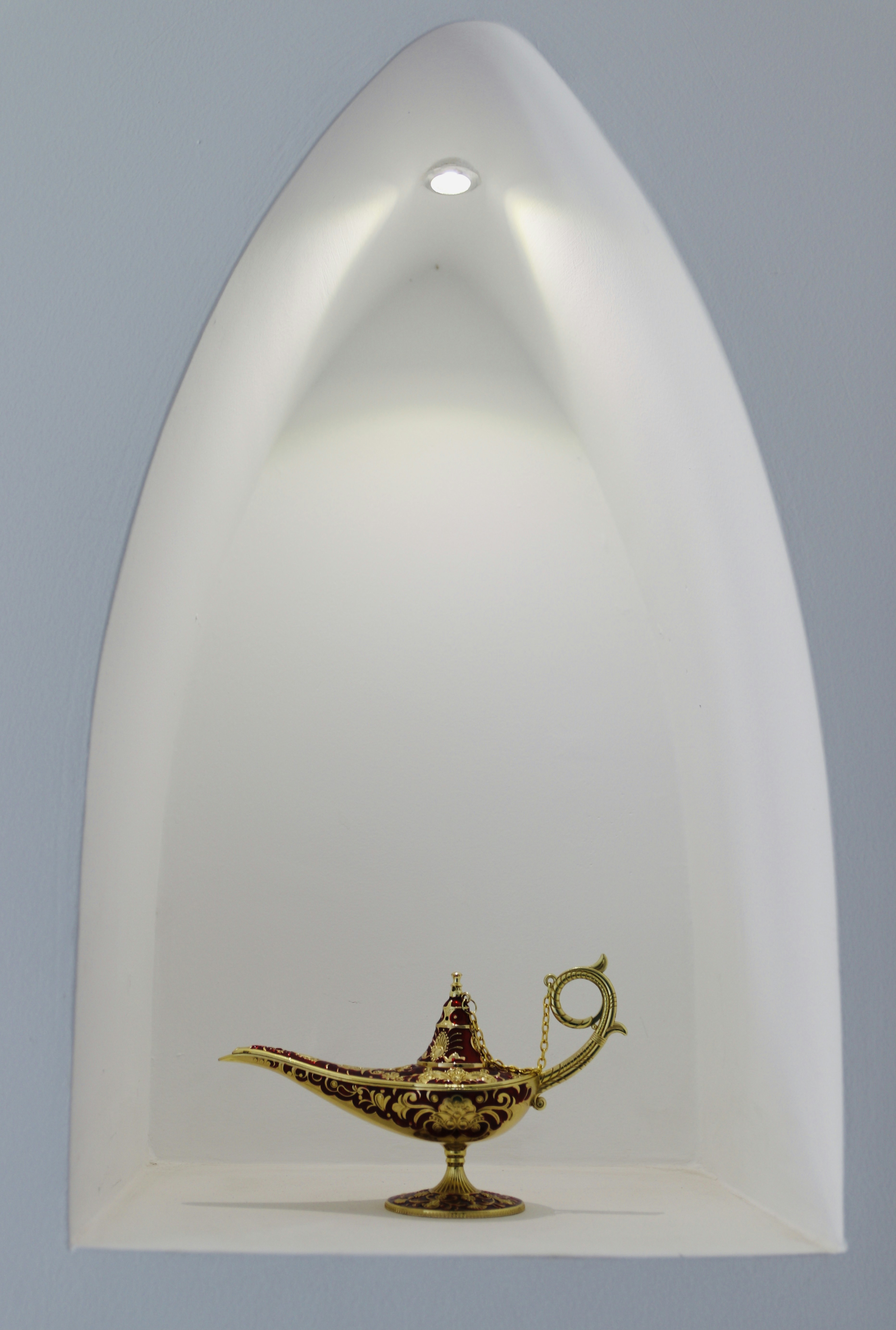 a gold hookah sitting on top of a white shelf