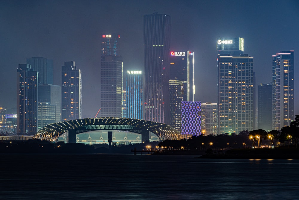 a city skyline at night with a bridge in the foreground