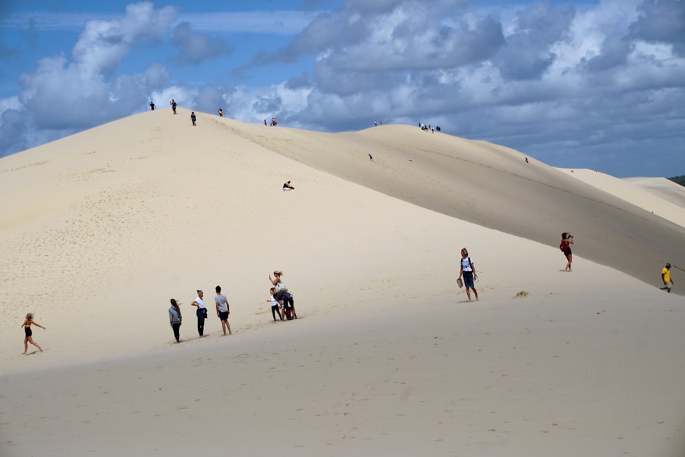 a group of people standing on top of a sandy hill