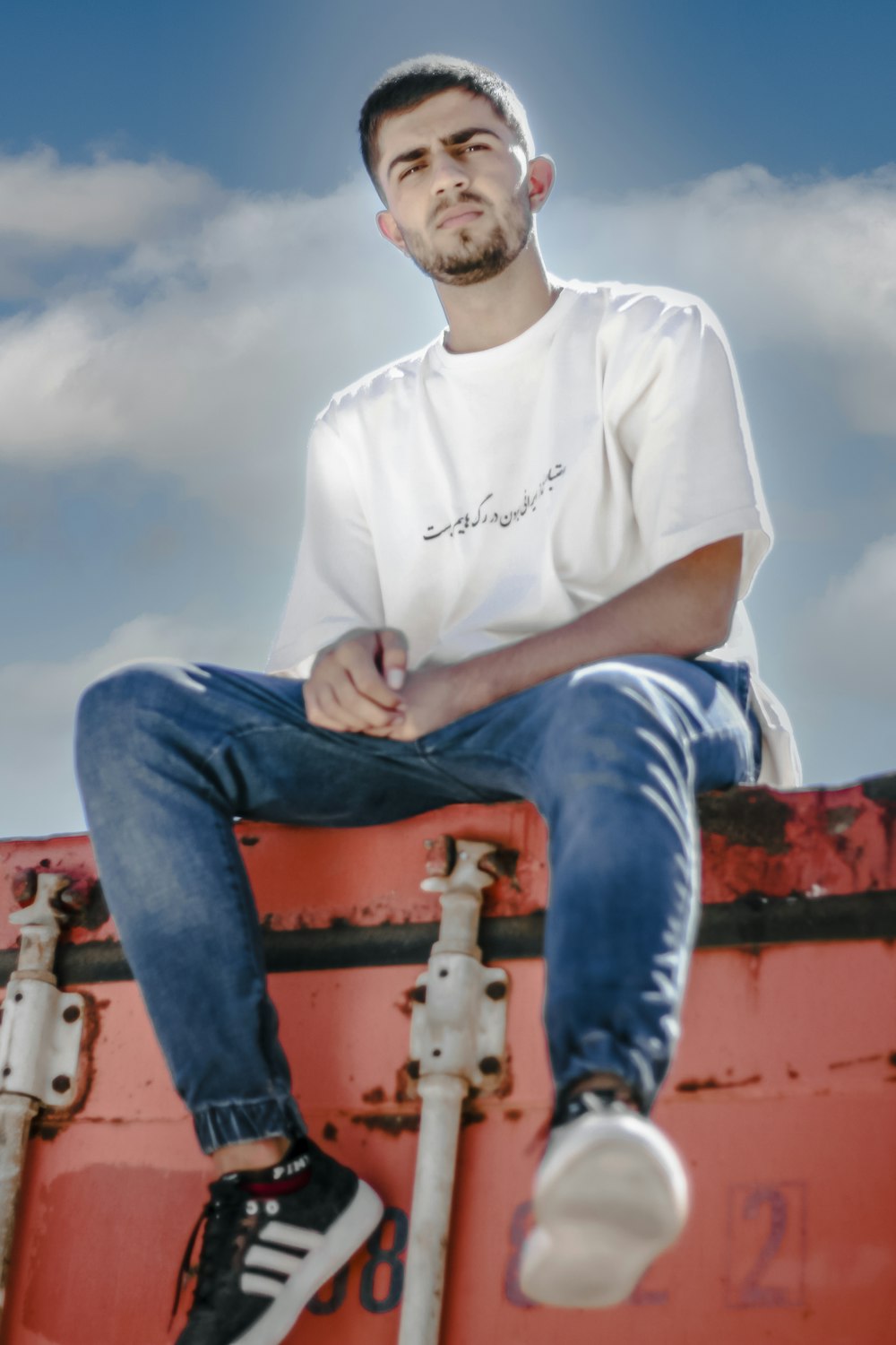 a man sitting on top of a red suitcase