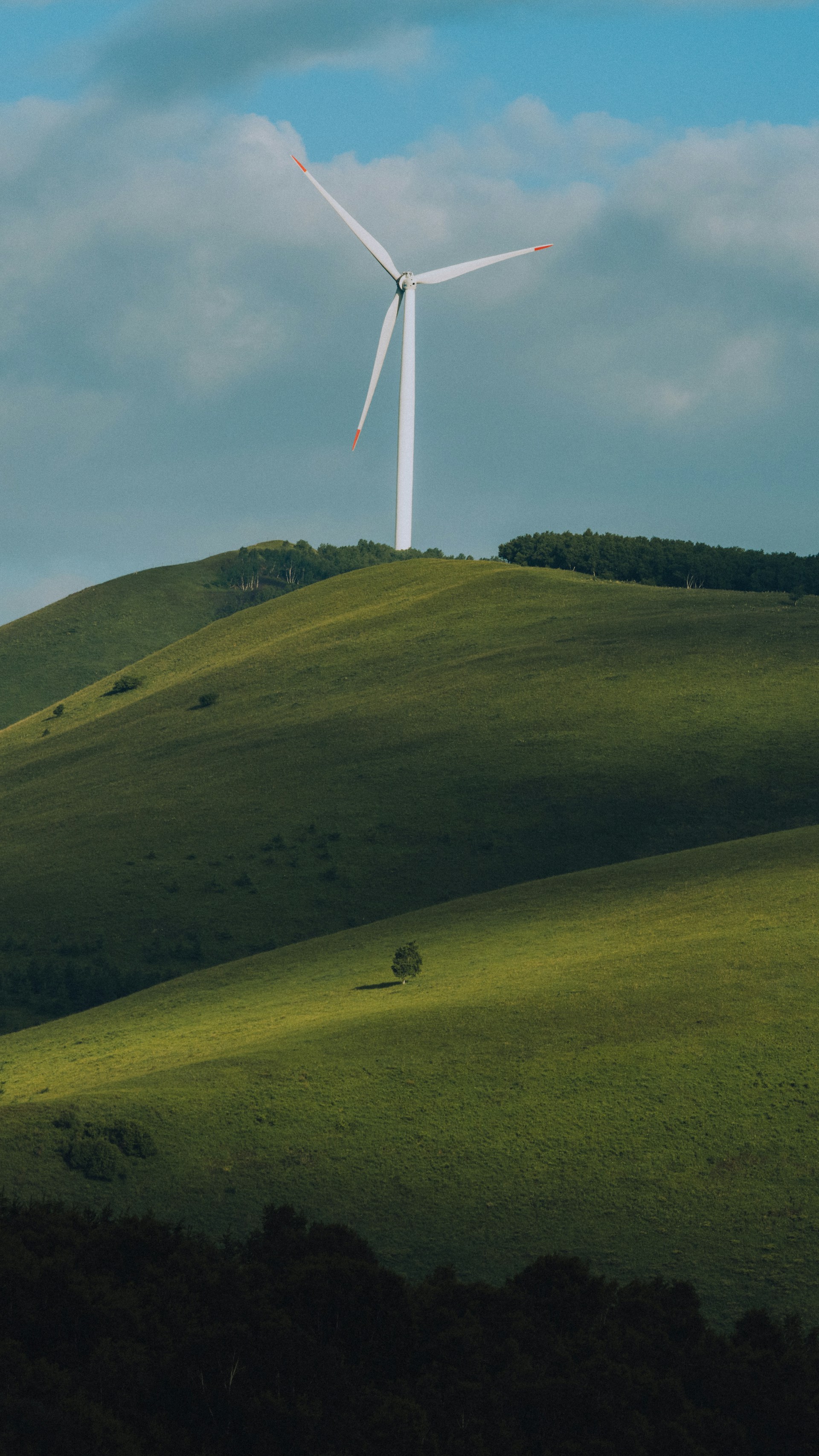 a wind turbine on top of a green hill