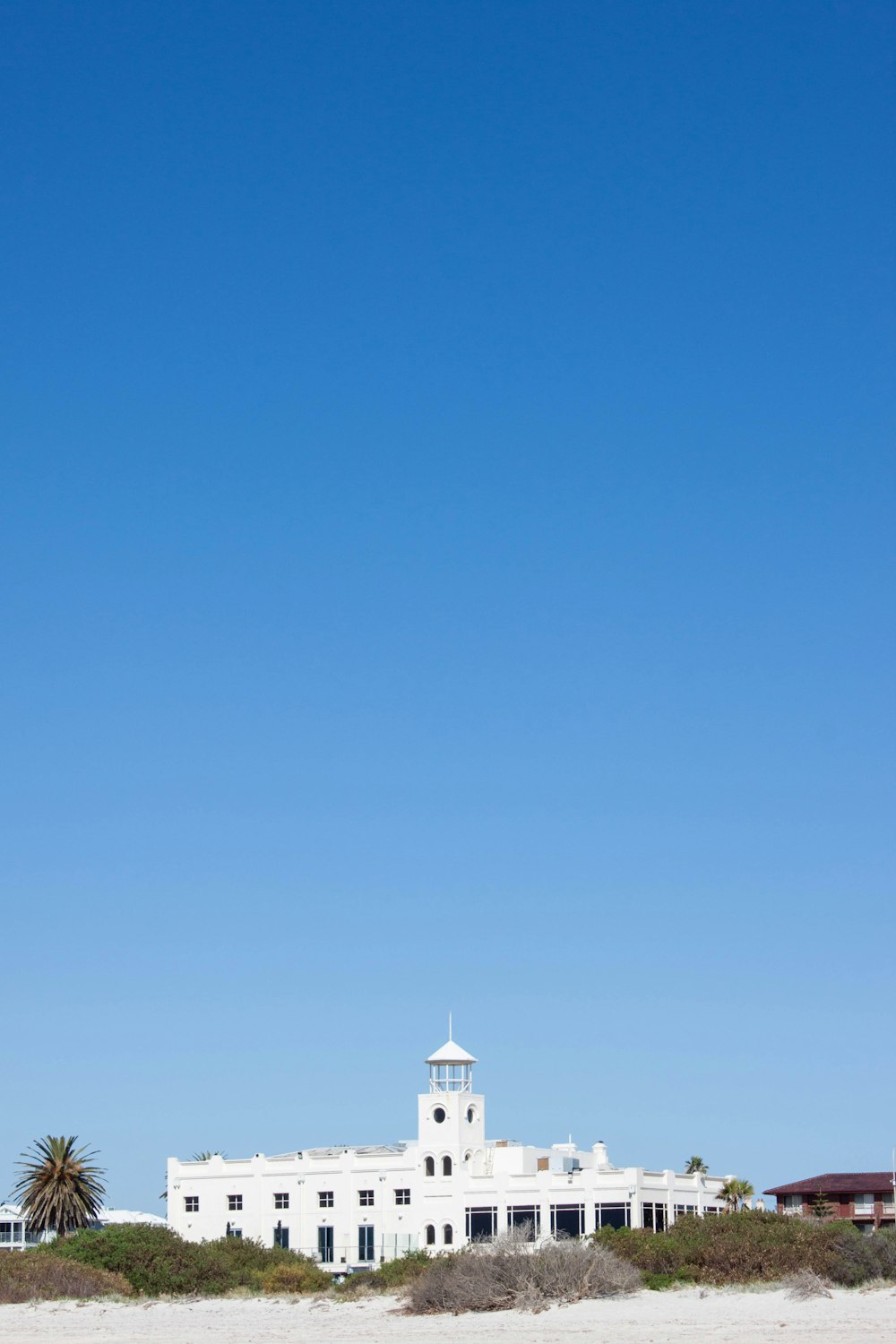 a white building on the beach with a blue sky in the background