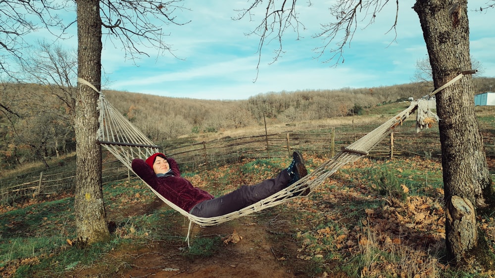 a person laying in a hammock between two trees