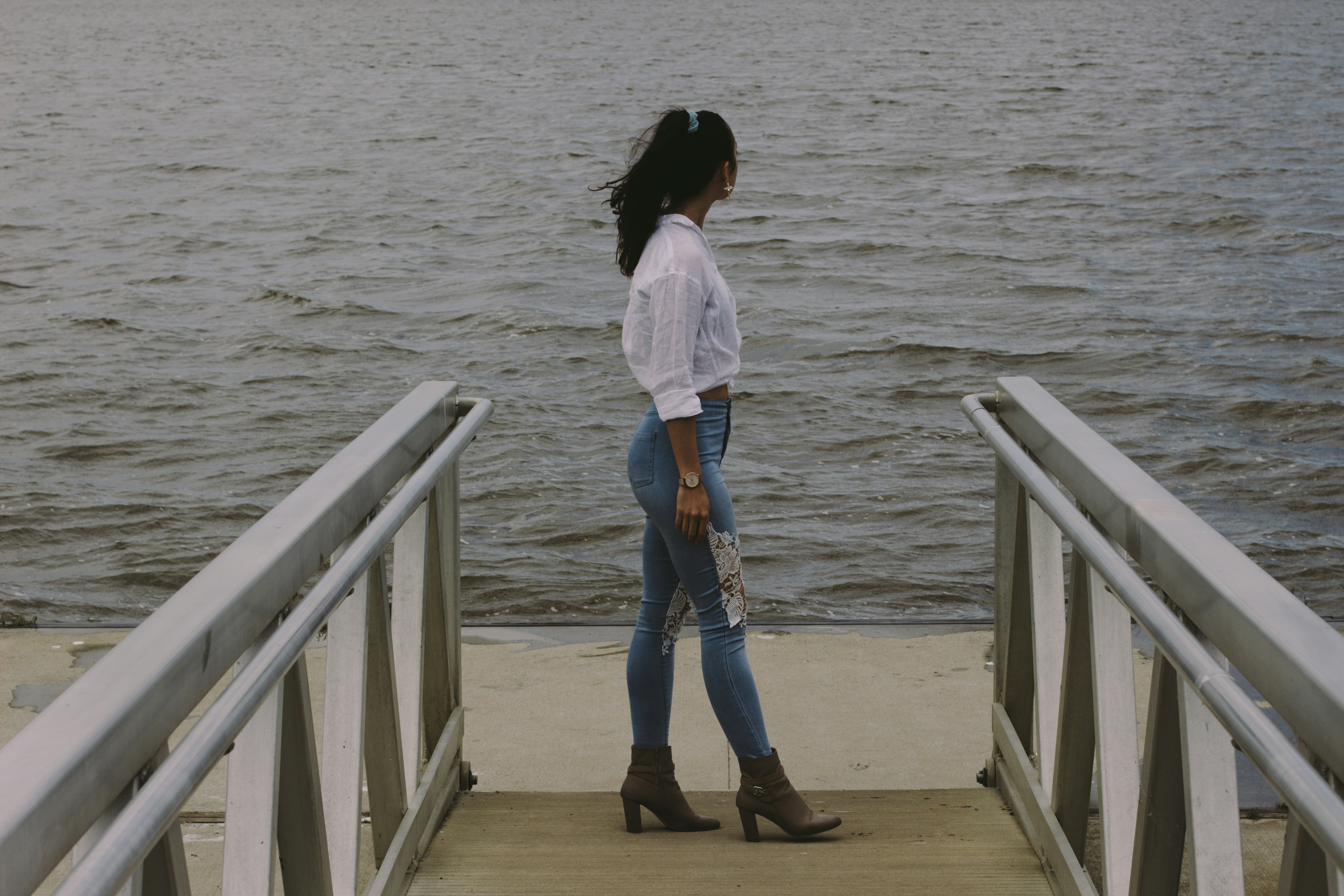 a woman standing on a pier next to a body of water