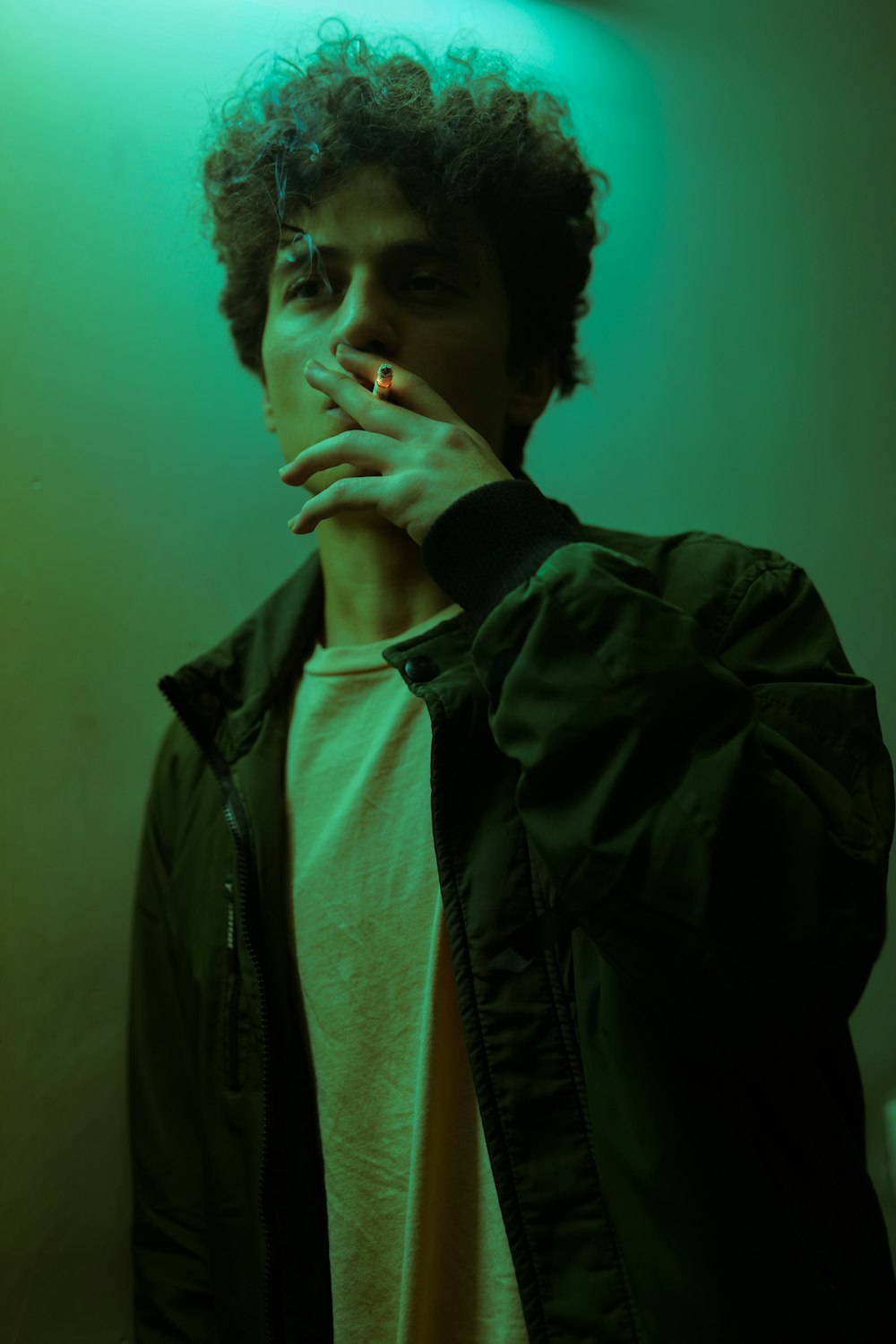 a young man smoking a cigarette in a dark room