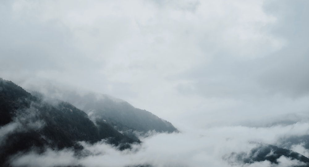 a group of clouds in the sky over a snow covered mountain