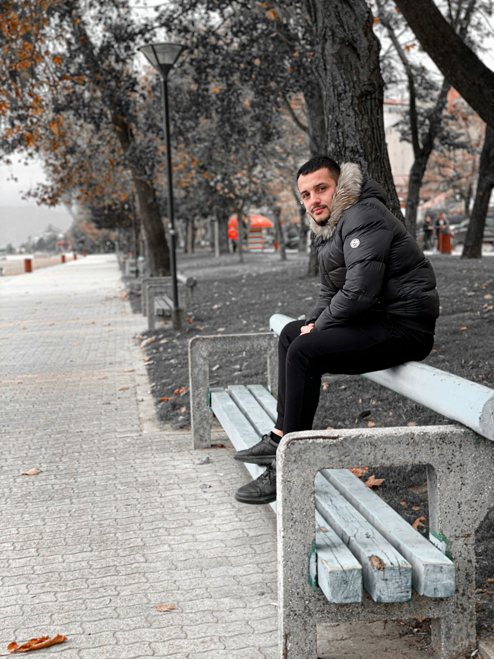 a man sitting on a bench in a park