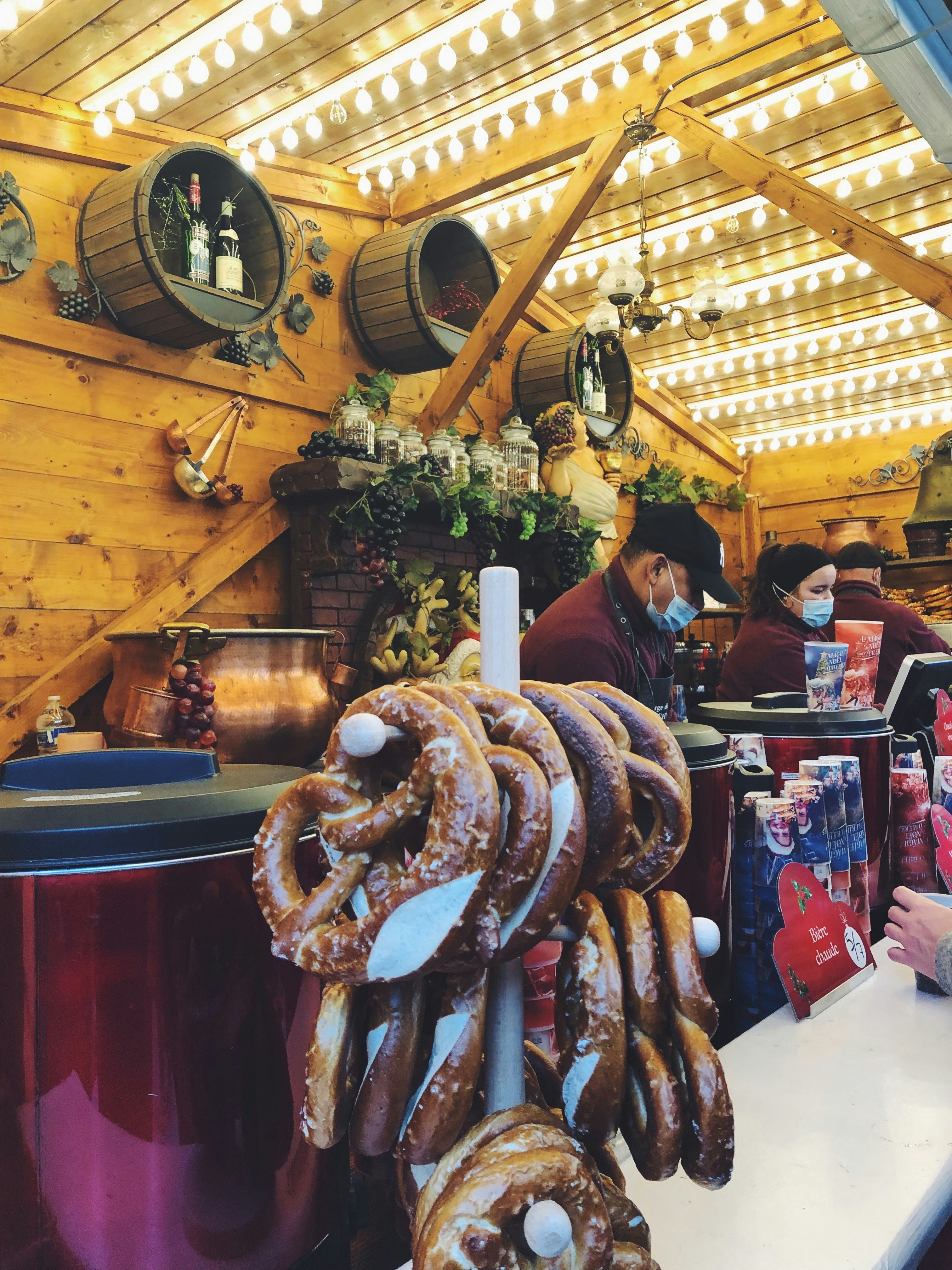 Alsatian village market with gingerbread, pretzels, and wine bottles on timber-framed stall, soft winter light