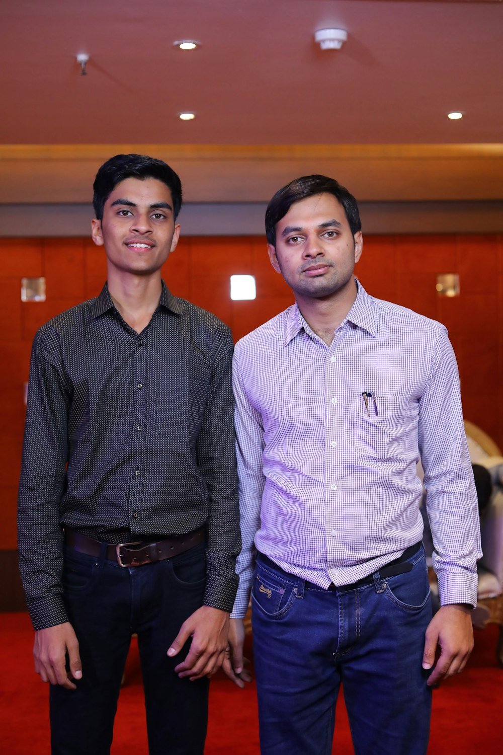 two men standing next to each other in a room