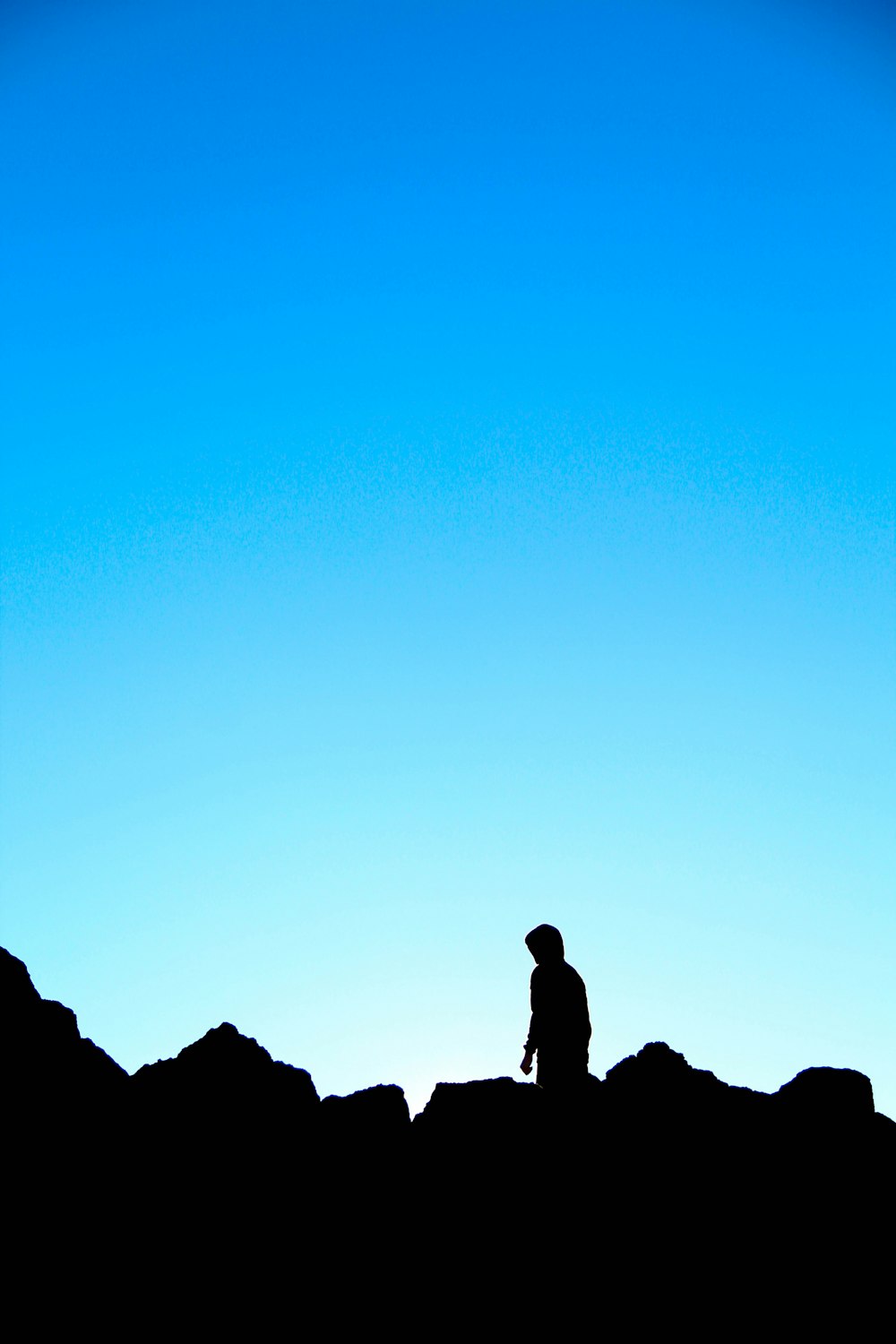 a silhouette of a person sitting on a hill