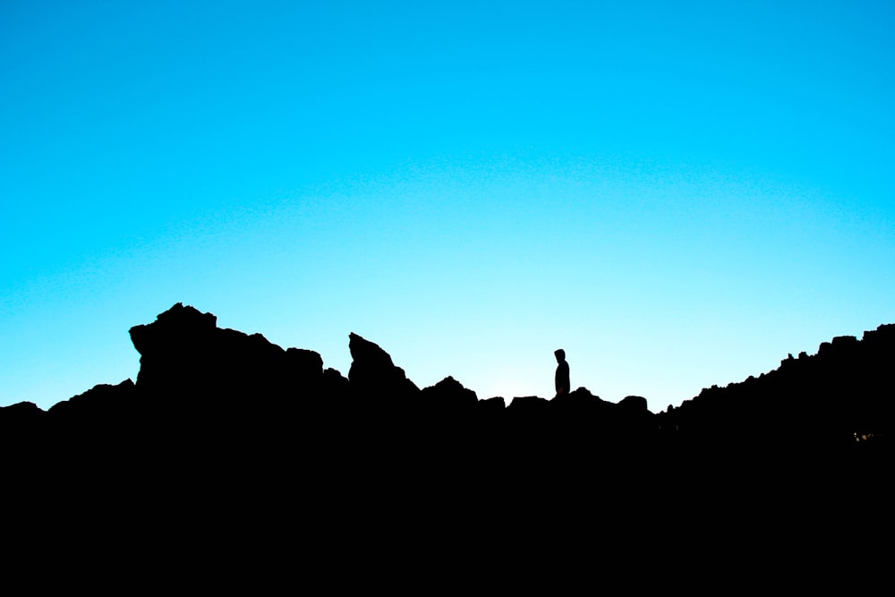 a silhouette of a person standing on top of a mountain