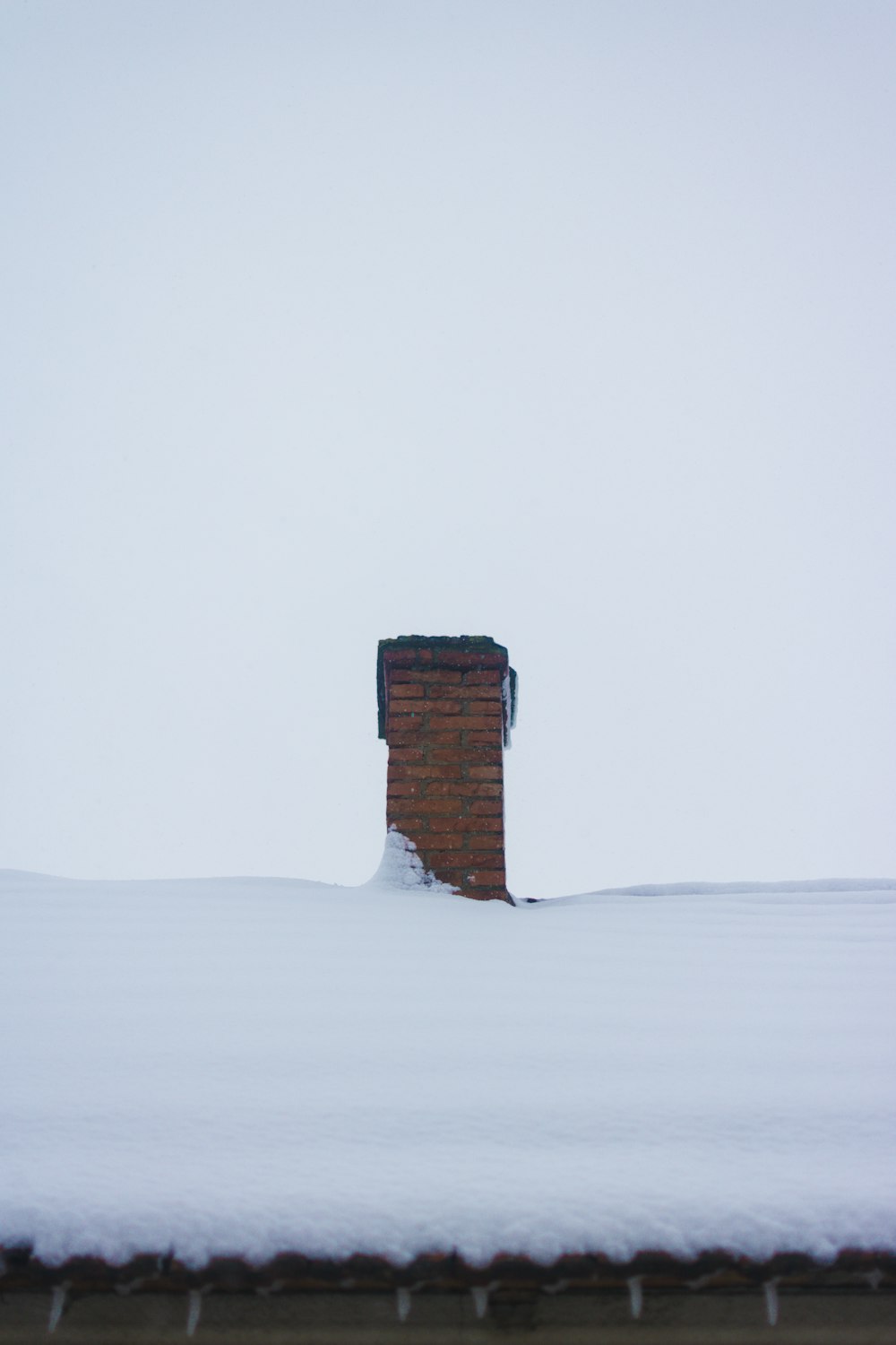 a chimney in the middle of a snow covered roof
