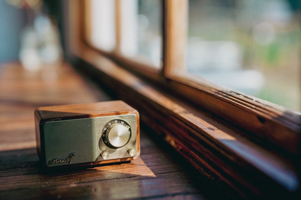 a radio sitting on top of a wooden table next to a window