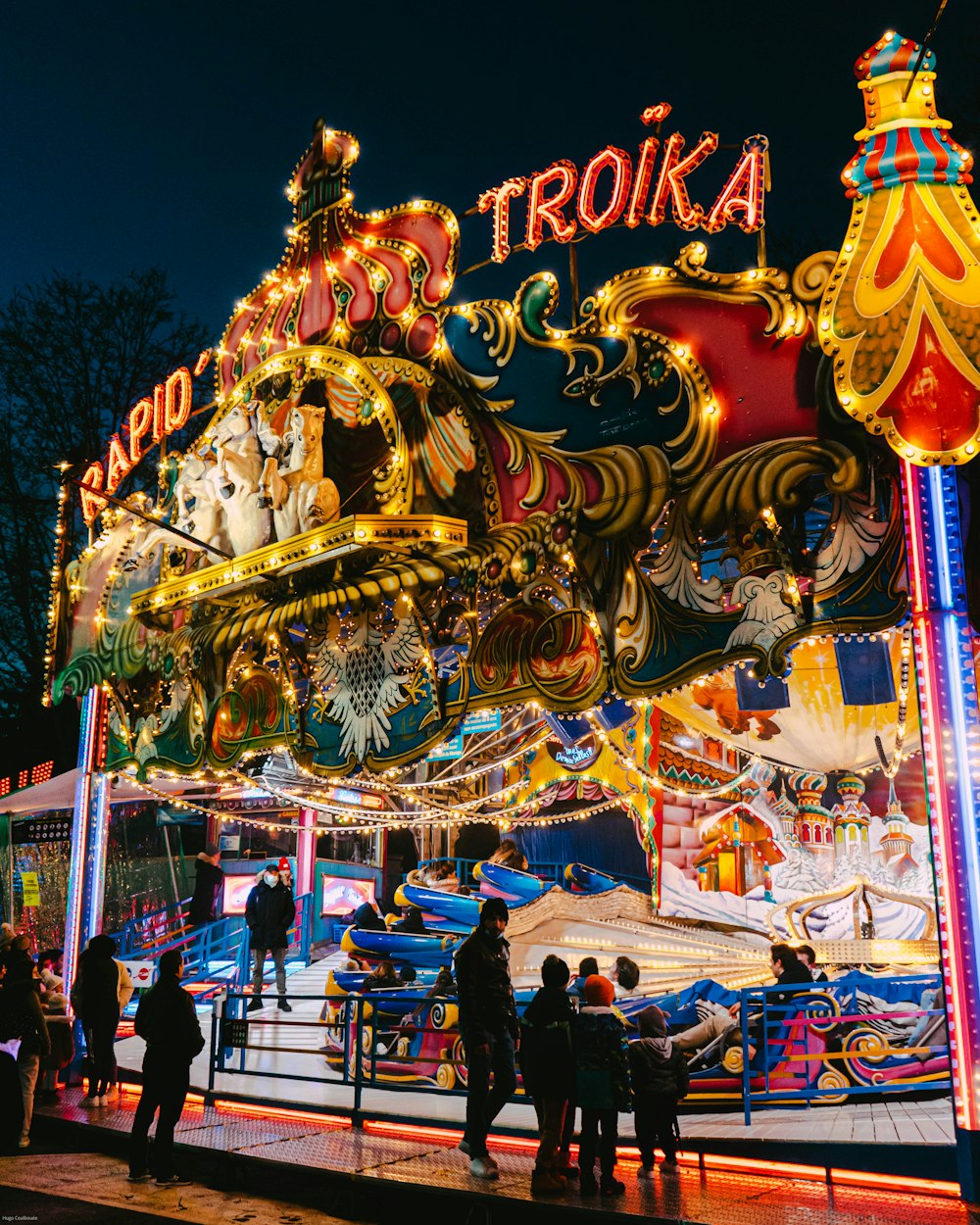 a merry go round at night with people standing around