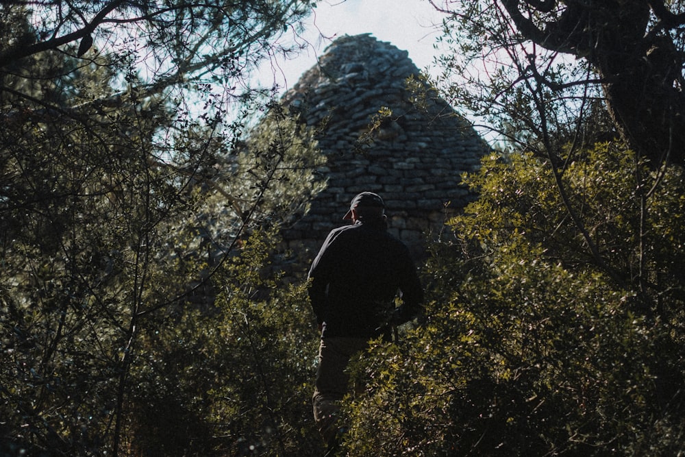 a man walking through the woods towards a building