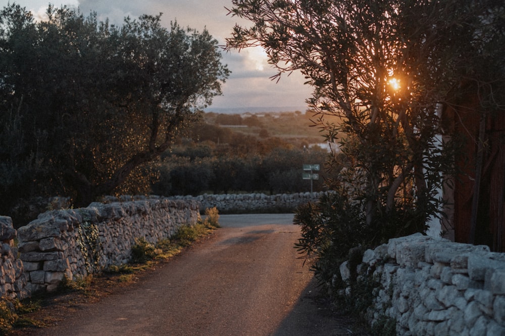 the sun is setting behind a stone wall