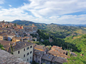 A charming Tuscan village street lined with colorful buildings and blooming flowers under a bright blue sky.