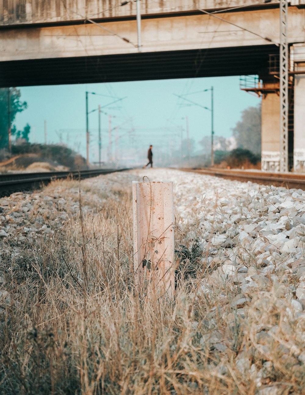 eine Person, die auf einem Bahngleis neben einer Brücke steht