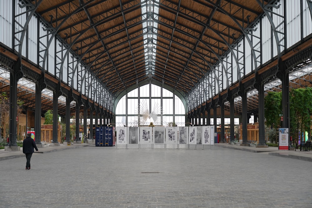 a person walking in a large building with lots of windows