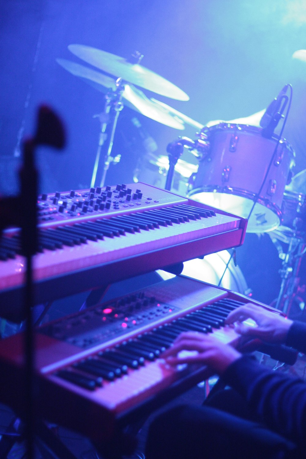 a person sitting at a keyboard in front of a drum set