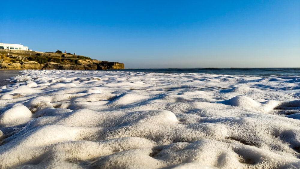 a beach covered in snow next to the ocean