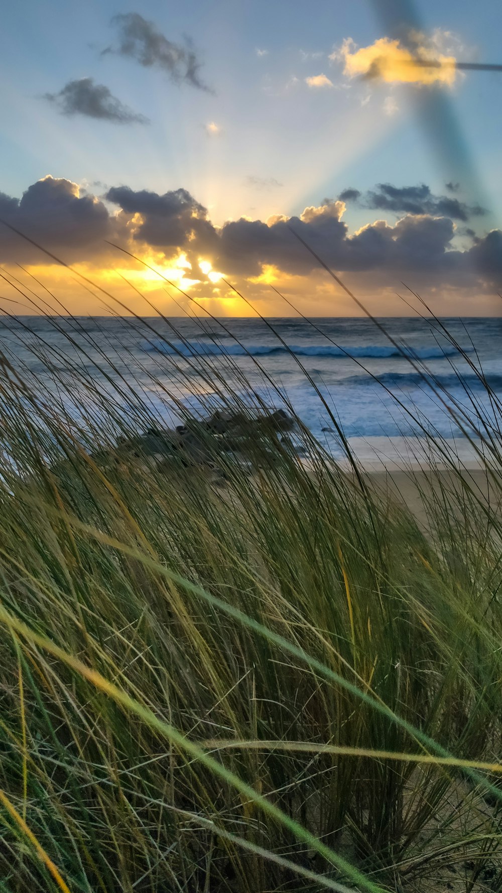 o sol está se pondo sobre o oceano e a praia