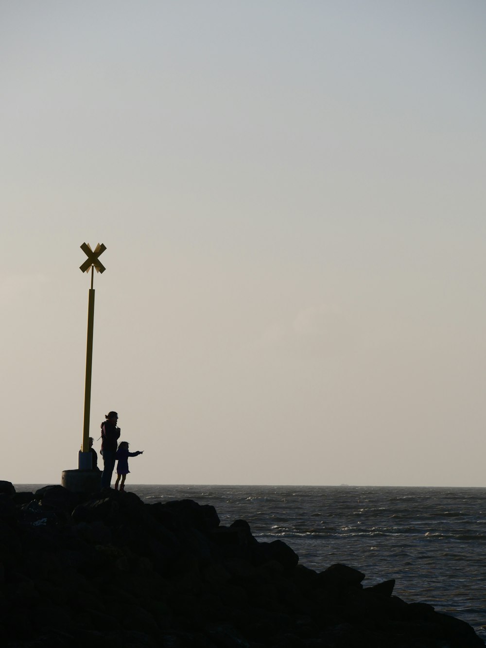 a couple of people standing on top of a rocky shore