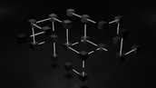 Black cubes connected by white rods forming a geometric, three-dimensional network-like structure against a dark background.