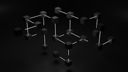 Black cubes connected by white rods forming a geometric, three-dimensional network-like structure against a dark background.