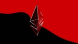 A metallic and reflective Ethereum logo is prominently placed in the foreground, set against a stark backdrop divided between bold black and vivid red colors.