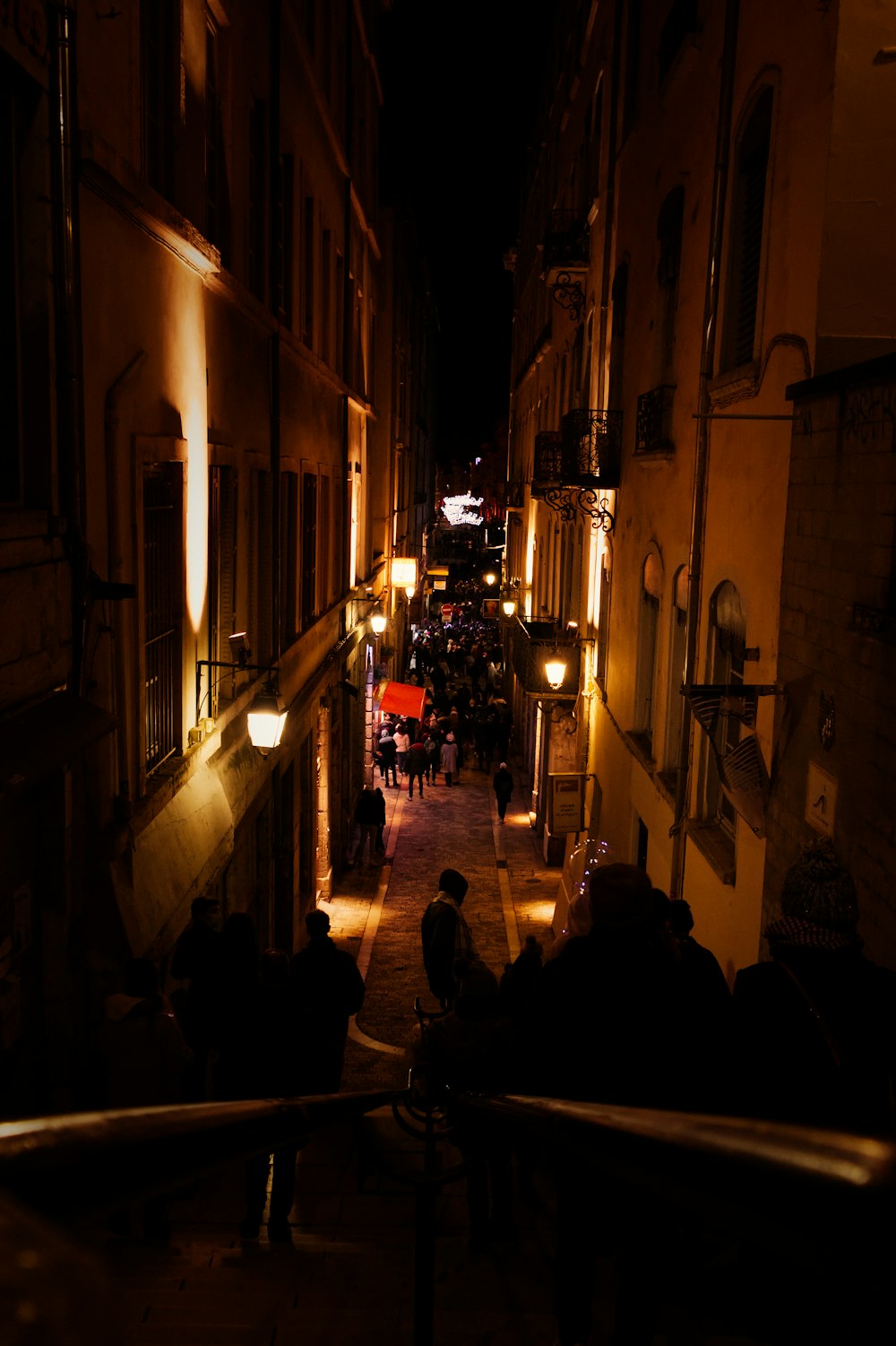 a group of people walking down a street at night