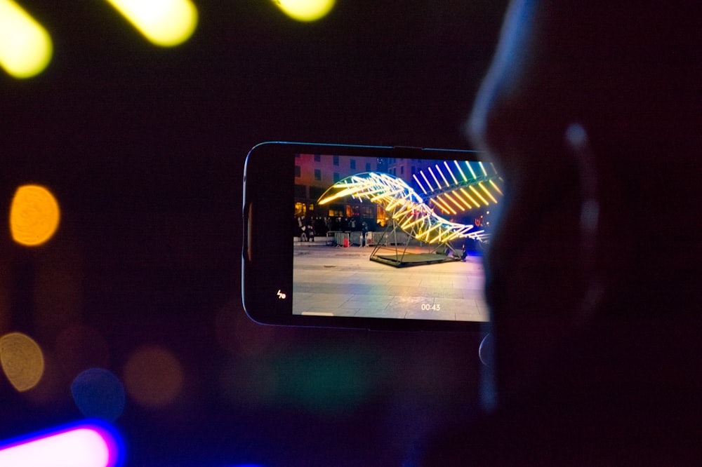 a person taking a picture of a colorful bridge