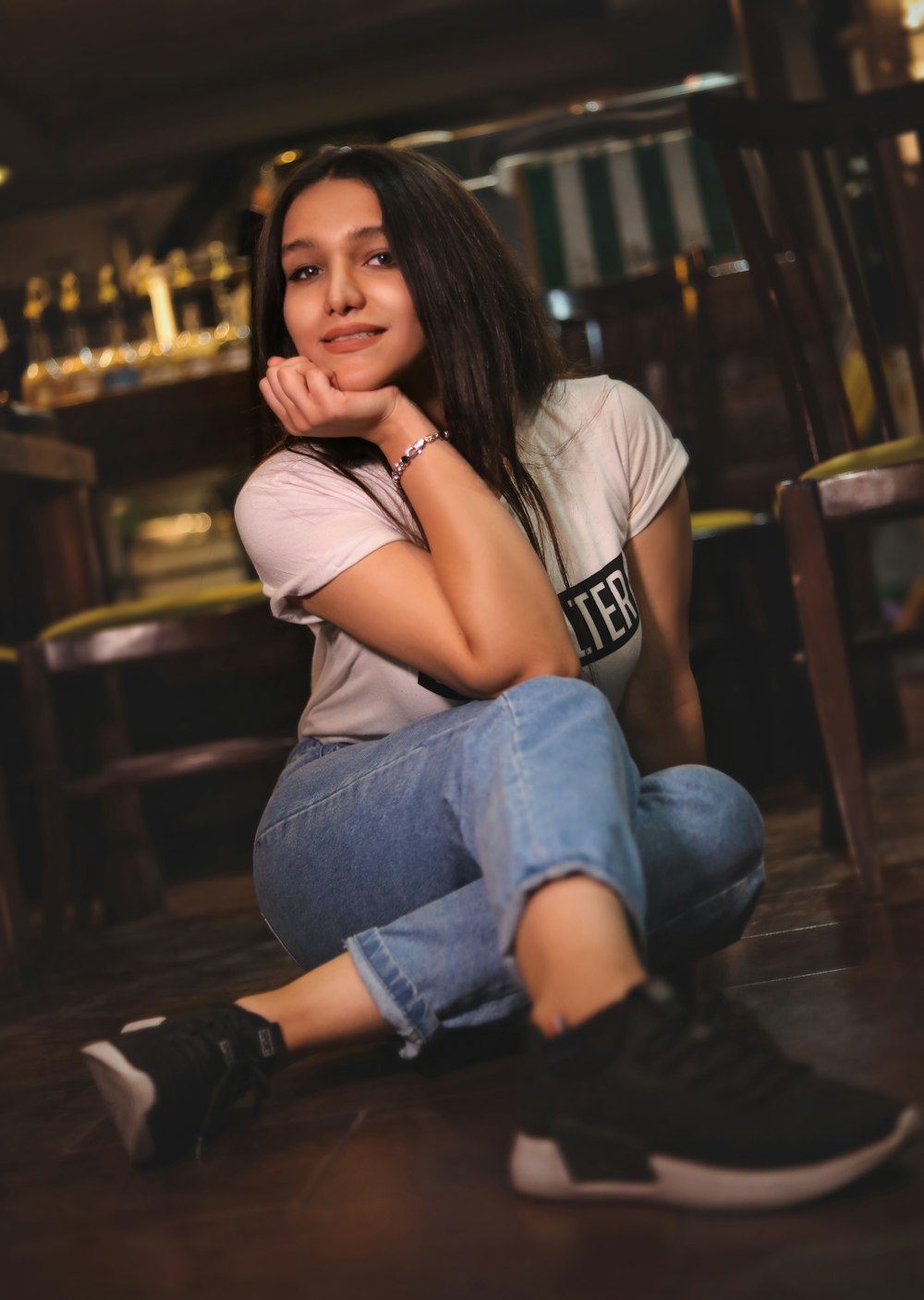 a woman sitting on the floor with her hand on her chin